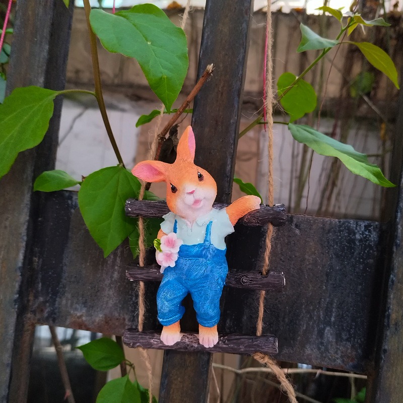 Rabbit ladder ornament hanging on a fence with green vines behind
