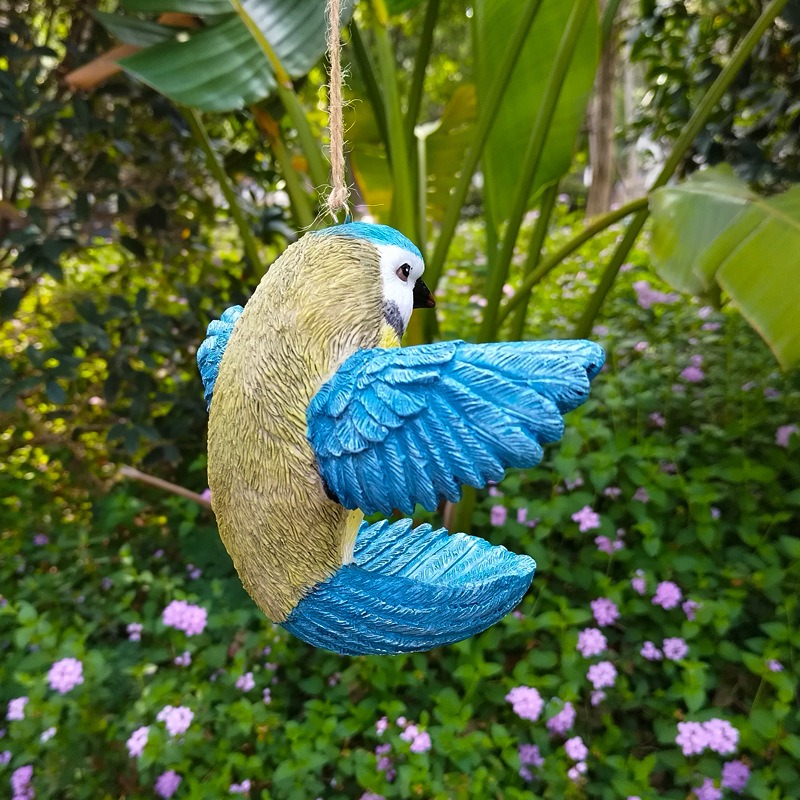 Side view of bird ornament hanging outdoors among green leaves