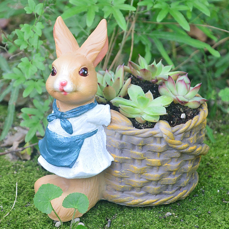Tan rabbit in blue apron beside a woven basket planter with succulents