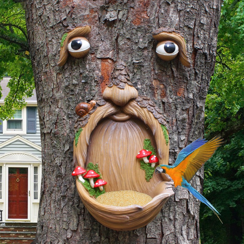 Tree face feeder on a trunk with a colorful parrot near the bowl