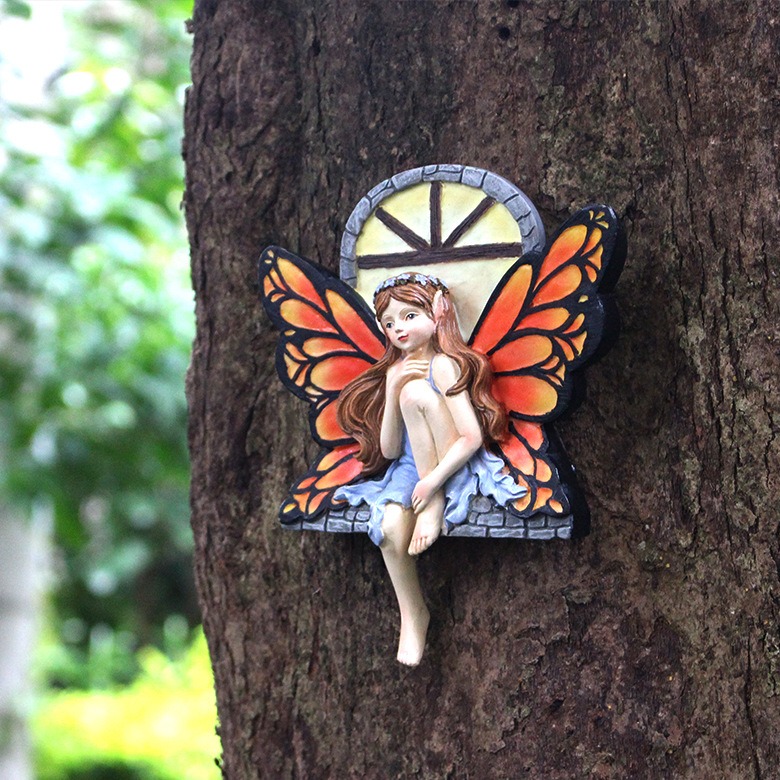Resin fairy ornament with stone arch detail on a garden surface