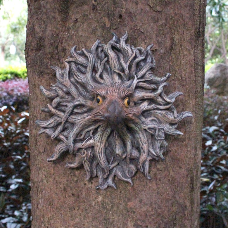 Eagle face wall decor mounted on a tree trunk in a garden