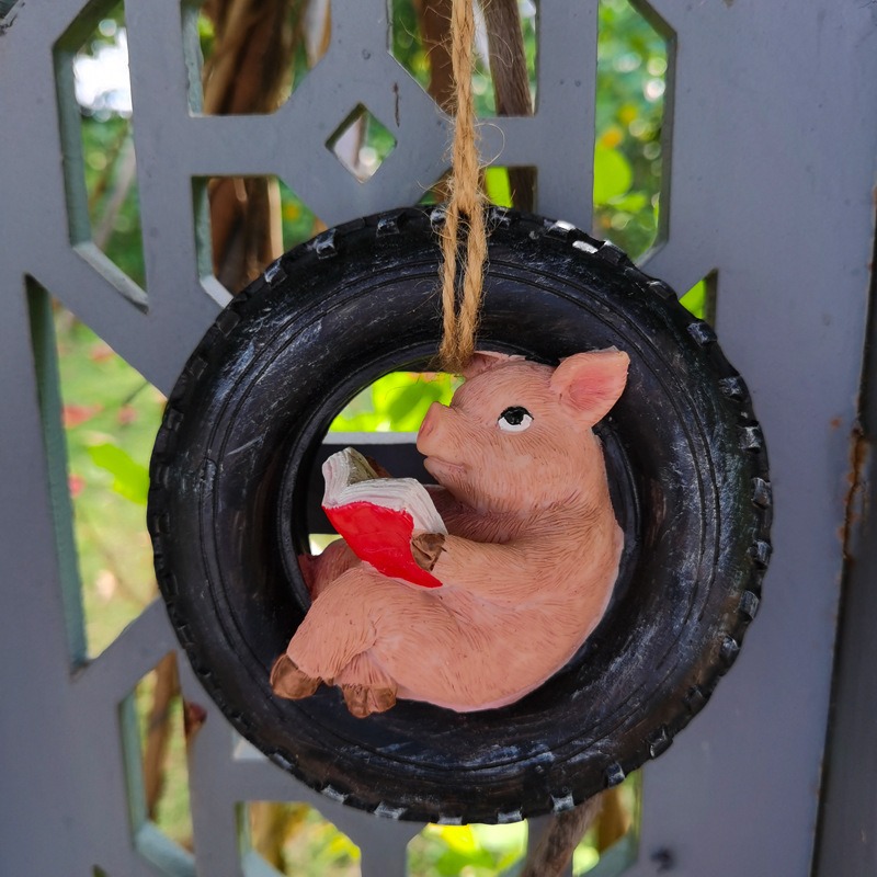 Close-up of pig in tire ring holding a red book on a lattice fence