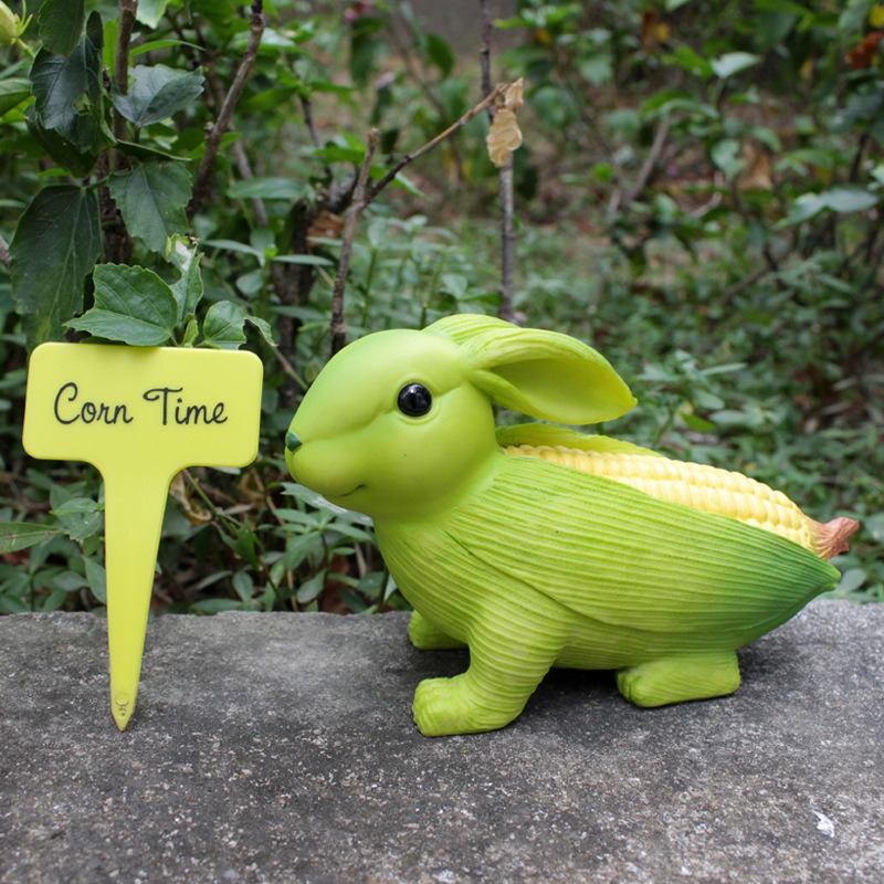 Corn rabbit ornament resting in a garden corner among greenery