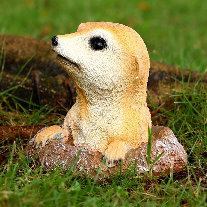 Side profile of meerkat ornament on rock with paws on the edge