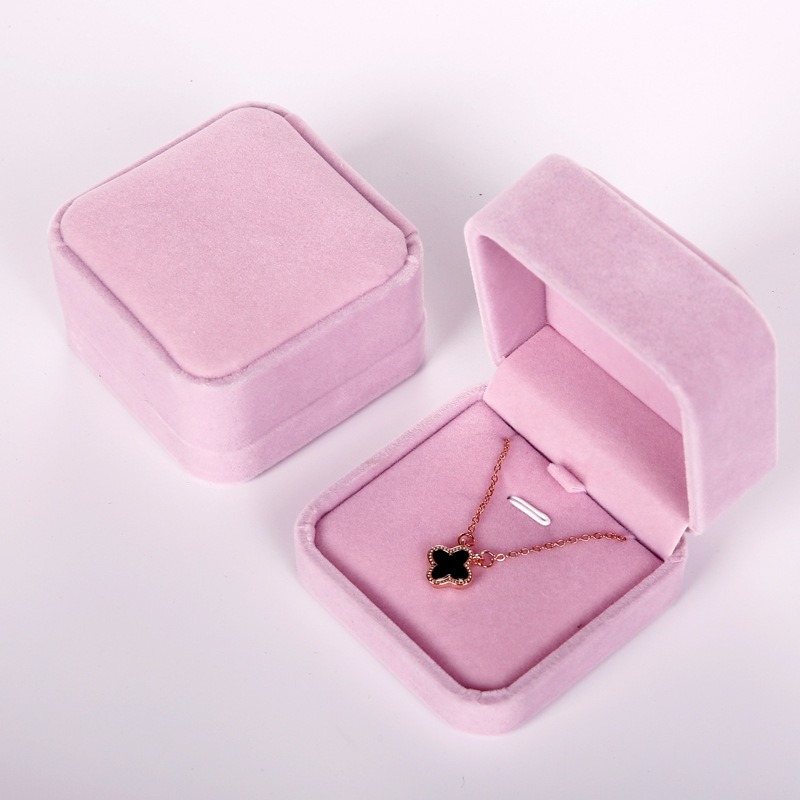 Pink velvet jewelry box open with a rose gold pendant on the pink lining