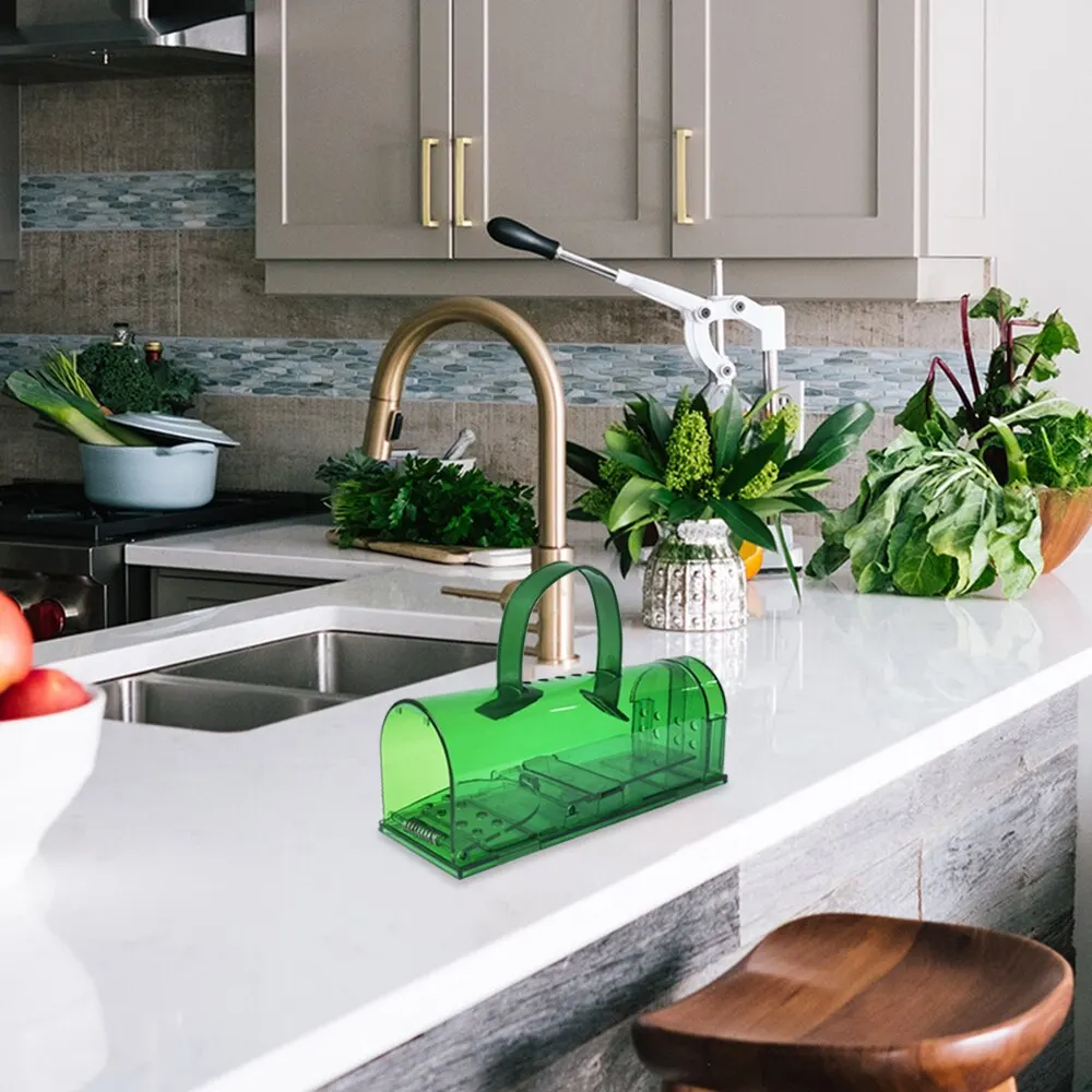 Green mousetrap on a white kitchen countertop beside a sink