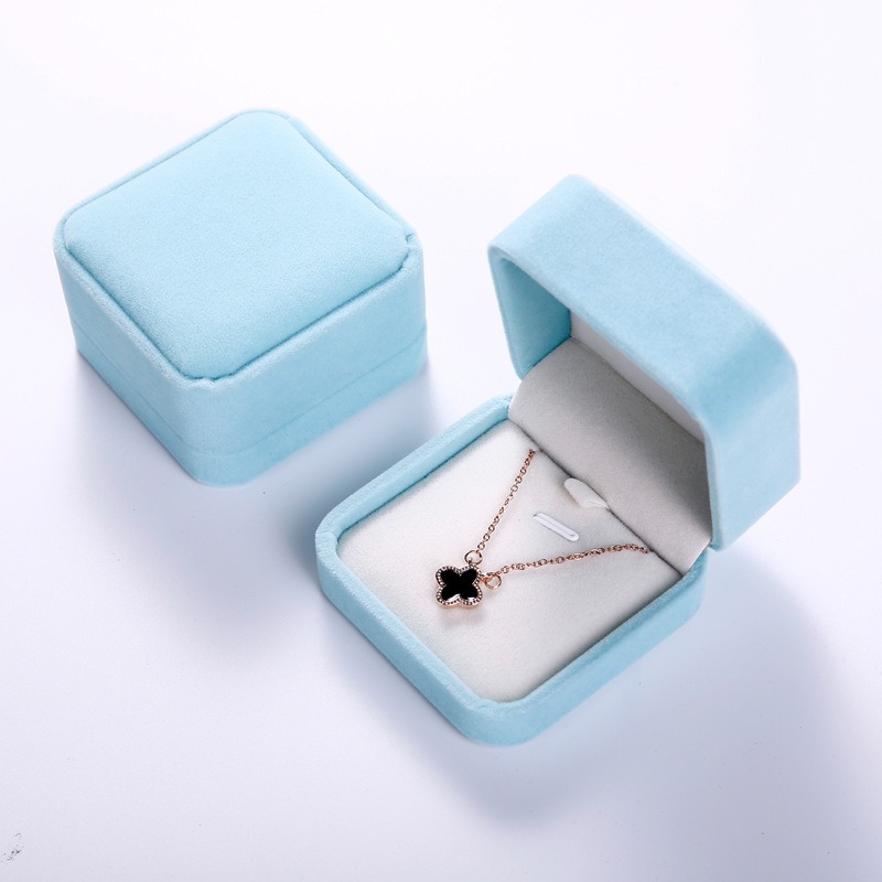 Light blue velvet box with a clover necklace hooked on the white pin