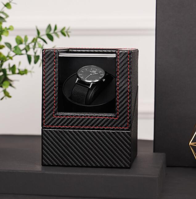 Closed carbon fiber watch winder with red stitched frame and watch visible through the window