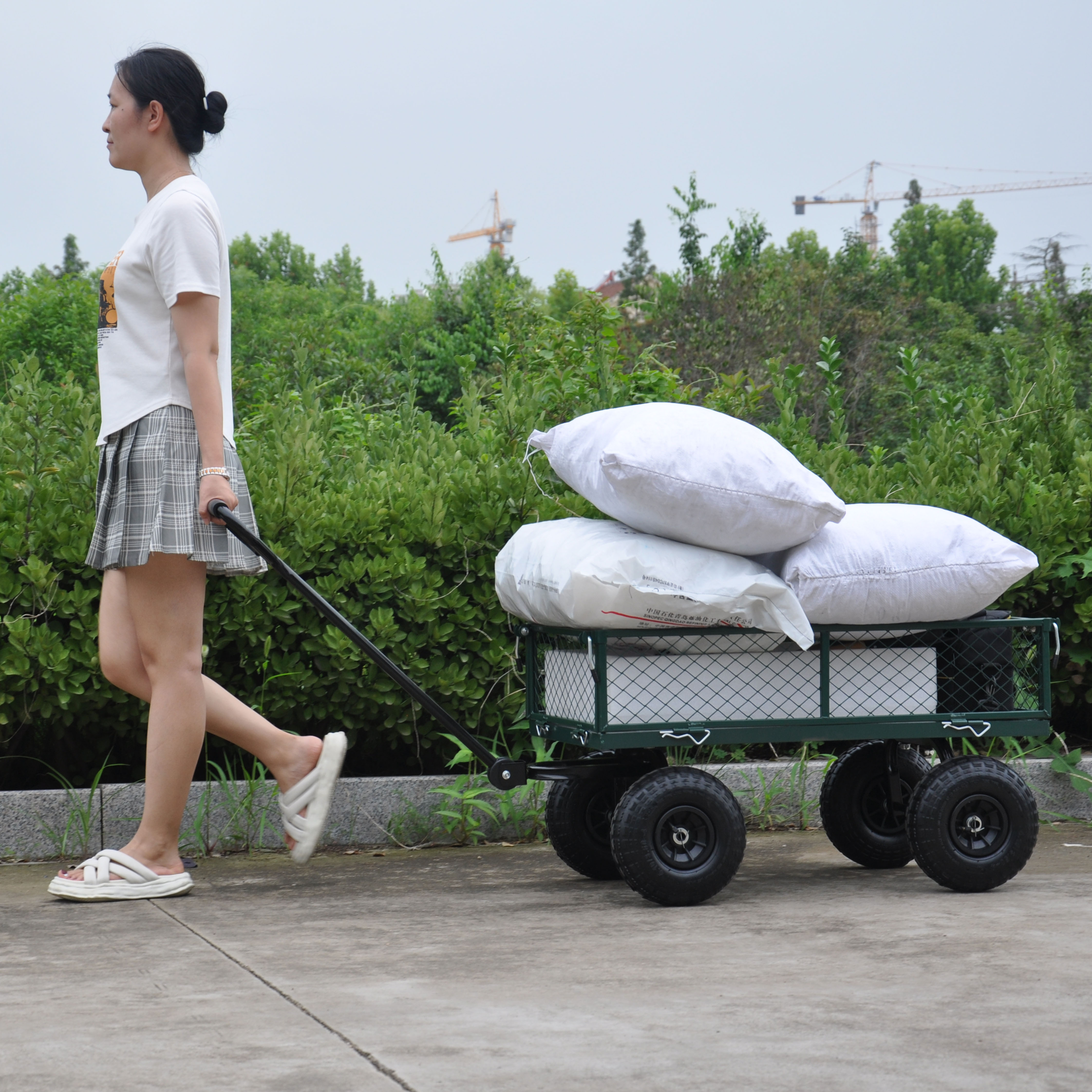 Person pulling a green mesh wagon along a paved path