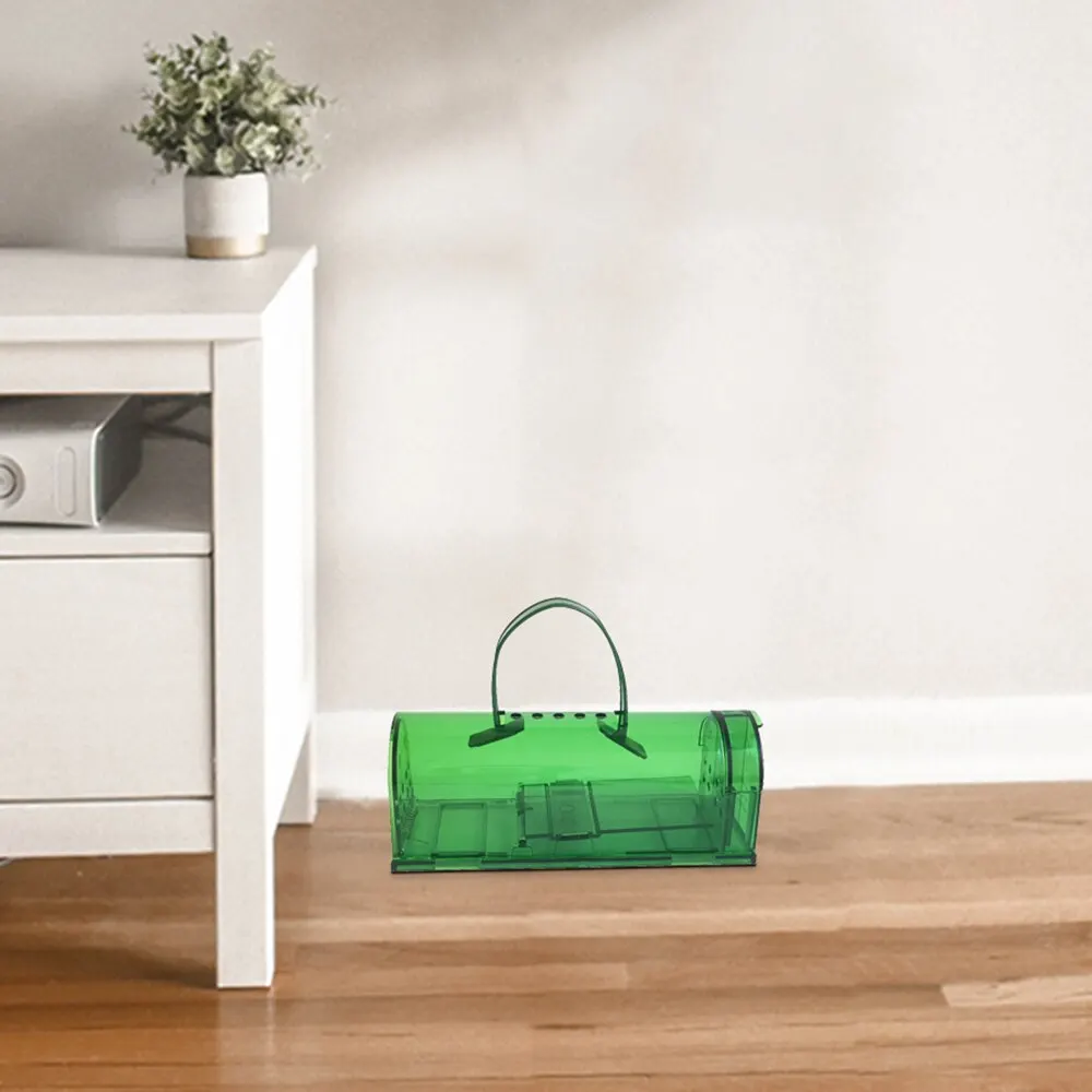 Green mousetrap on hardwood floor beside a white side table