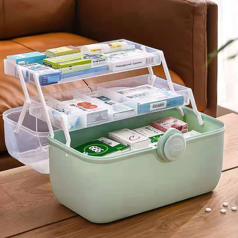 Mint-green first aid box with lid open and fold-out tiers holding medicine boxes