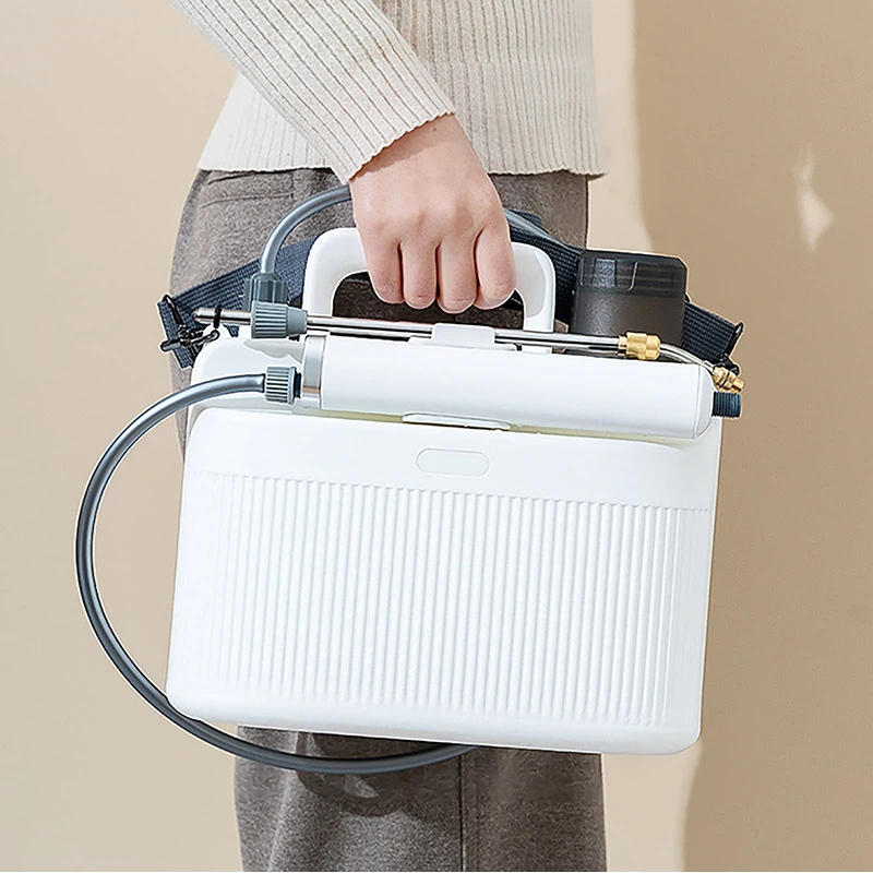 Person carrying the white sprayer by its handle and shoulder strap