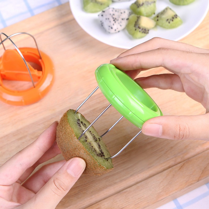 Hand pressing a green ring of steel wires through a halved kiwi