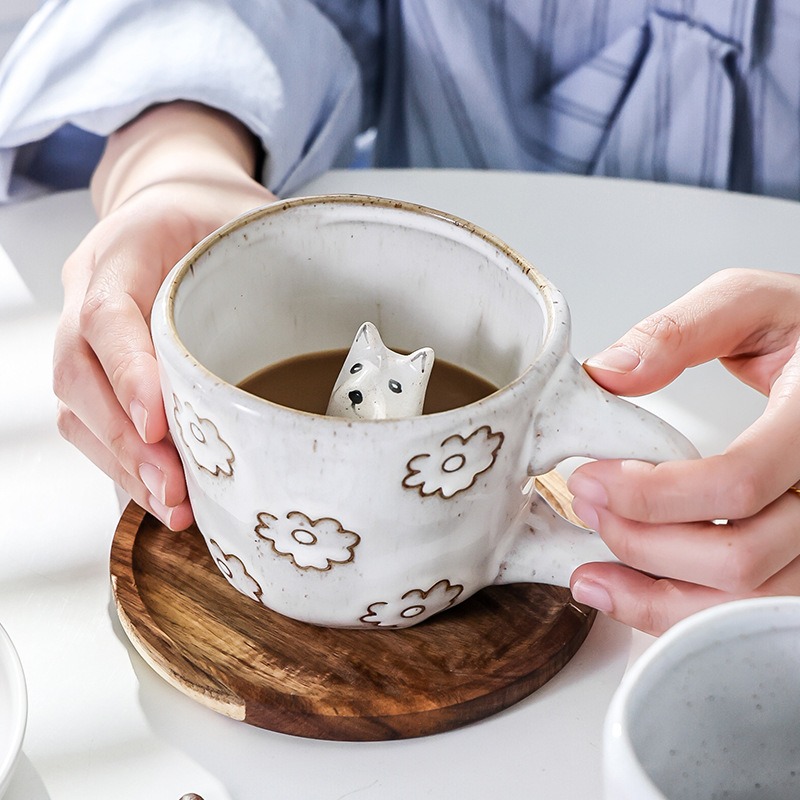 Hands holding cream mug with fox figure peeking out of the coffee