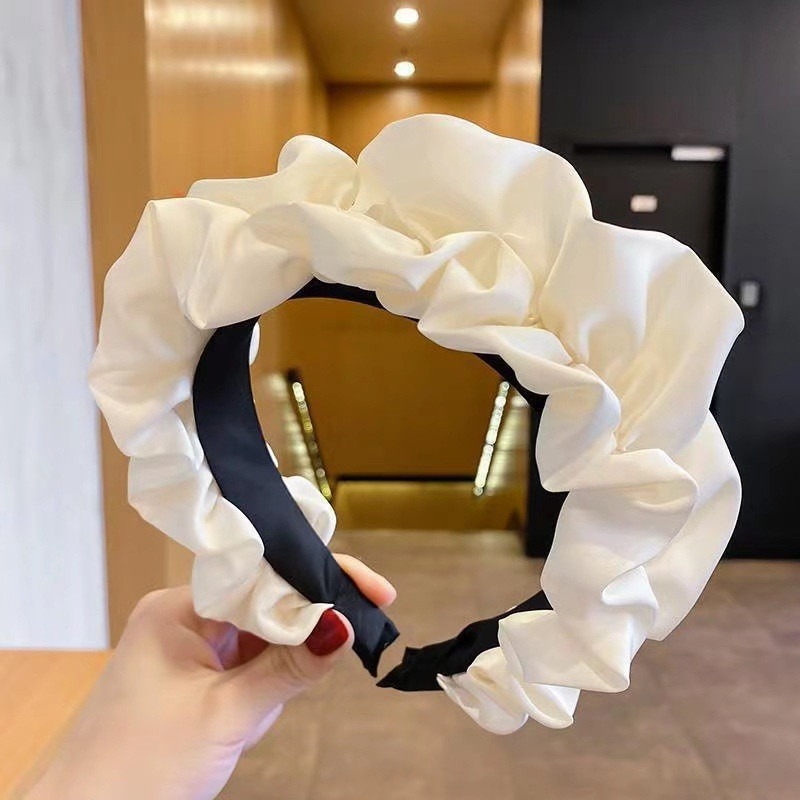 White wide headband framing the face with glossy folds