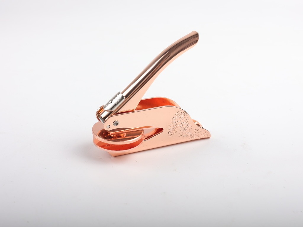 Hand pressing a rose gold seal onto a cream envelope flap