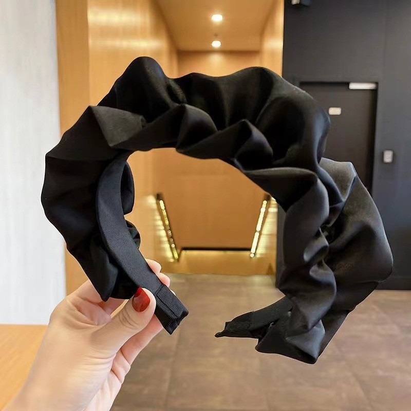Black headband close view of glossy folded satin-like fabric
