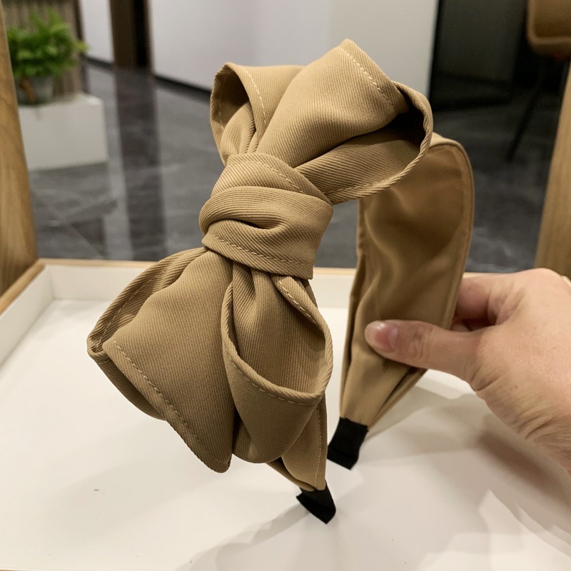 Tan bow headband close-up showing matte twill texture