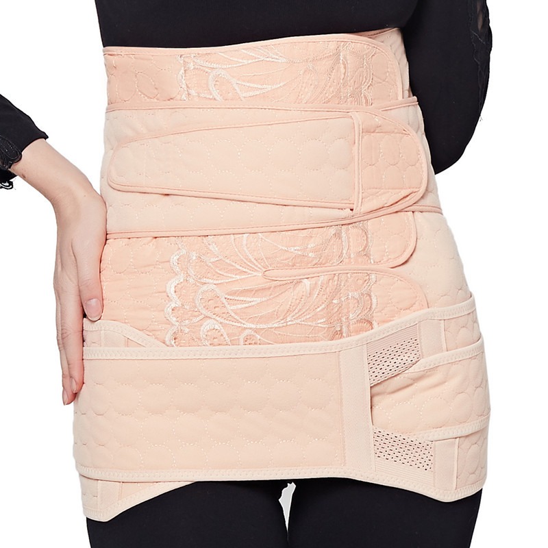Woman wearing postpartum strap set, looking at herself in mirror with gentle confidence