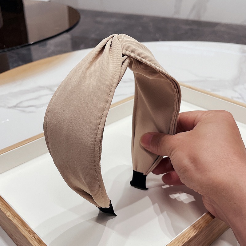 Beige headband showing smooth fabric and stitched edge