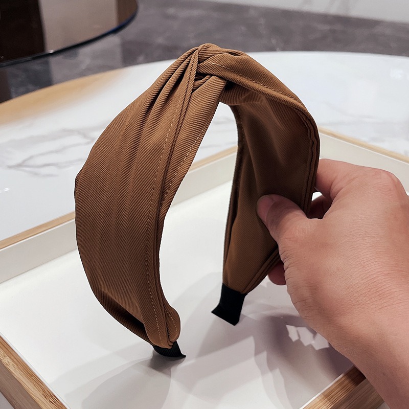 Brown headband held to show sculptural crossed bow
