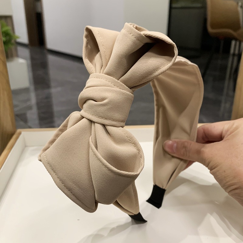 Beige bow headband showing wide structured band fit