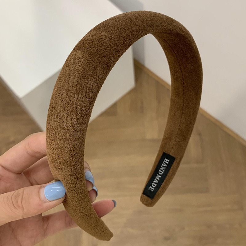 Hand holding thick brown padded velvet headband