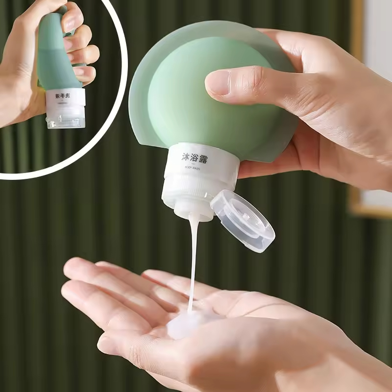 Sage green travel bottle dispensing body wash into an open palm