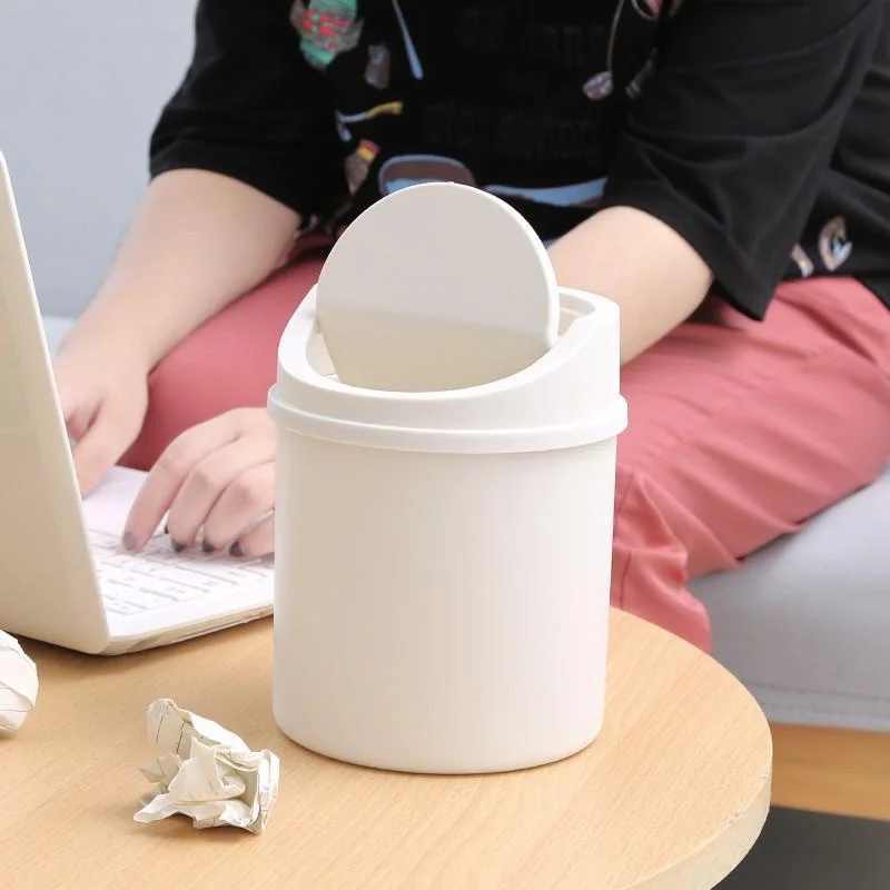 White desktop trash can with lid open beside a laptop on a wooden table