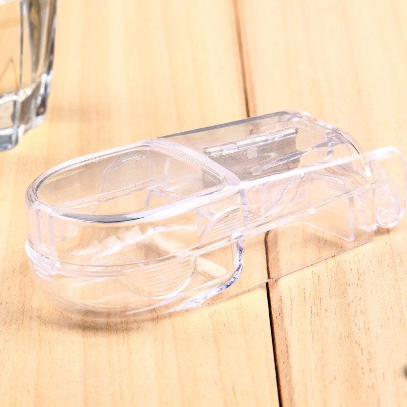 Clear crystal pill cutter on a wood surface with the blade visible through the lid