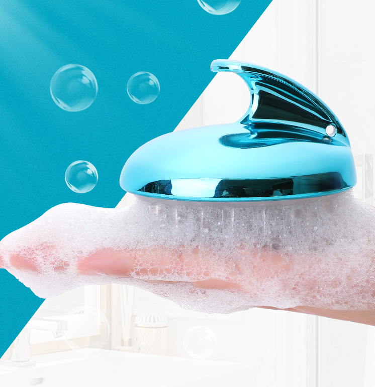 Blue scalp massager lathered with foam in a hand, bubbles floating against a bright background