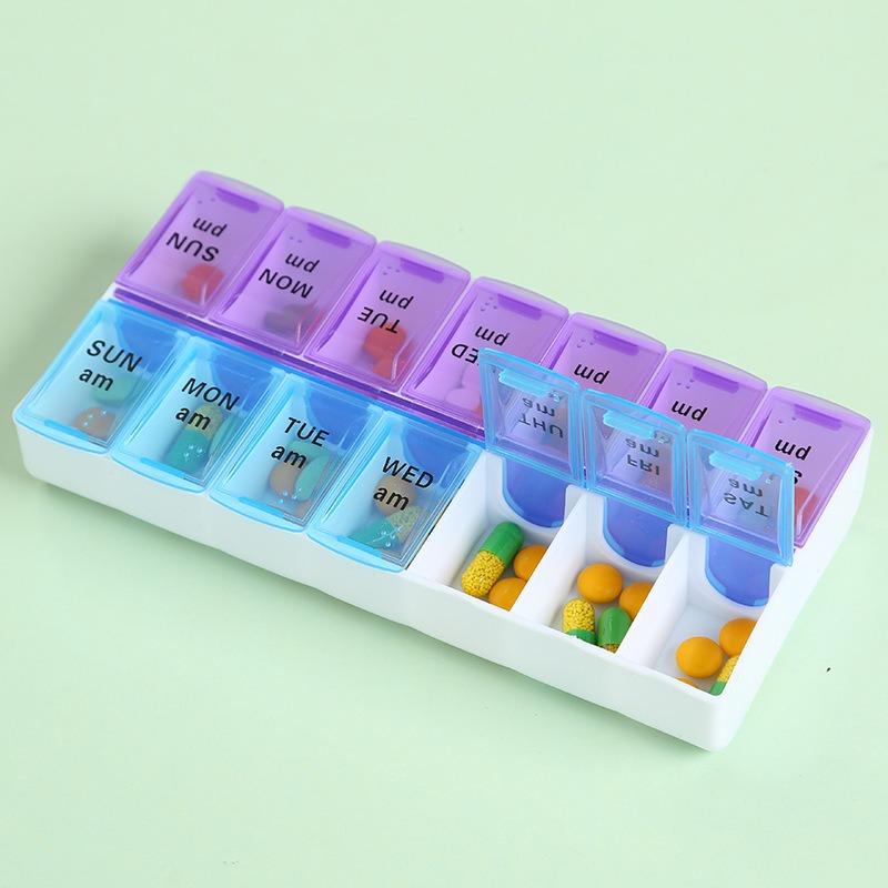 Weekly pill organizer loaded with capsules and tablets, lids partly open