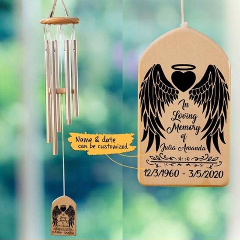 Wind chime hanging outdoors by a pond with engraved wood pendant