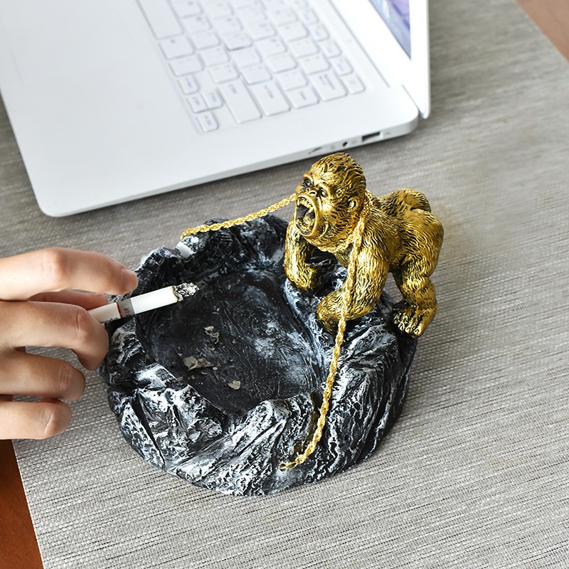 Cigarette tapped over the rock ashtray on a desk beside a laptop