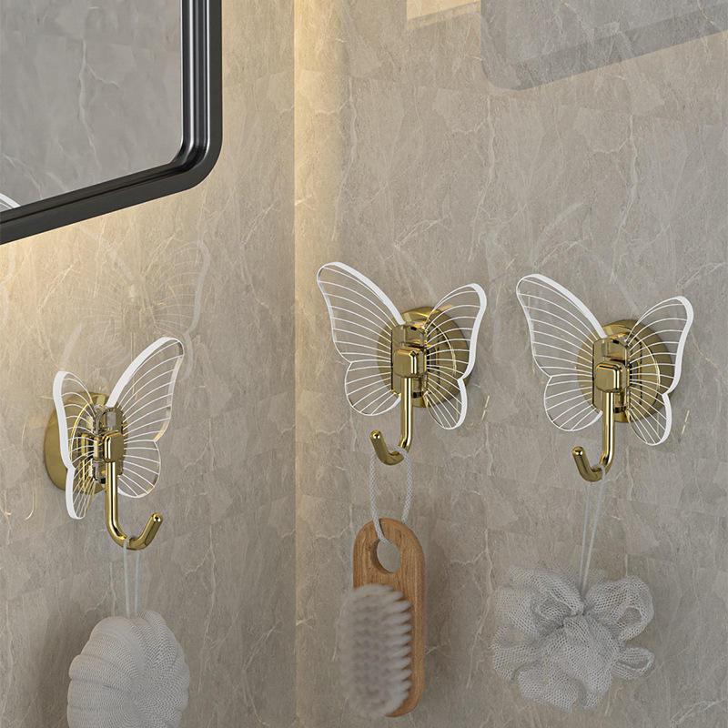 Butterfly hooks on bathroom tile holding a loofah, brush and mesh bag