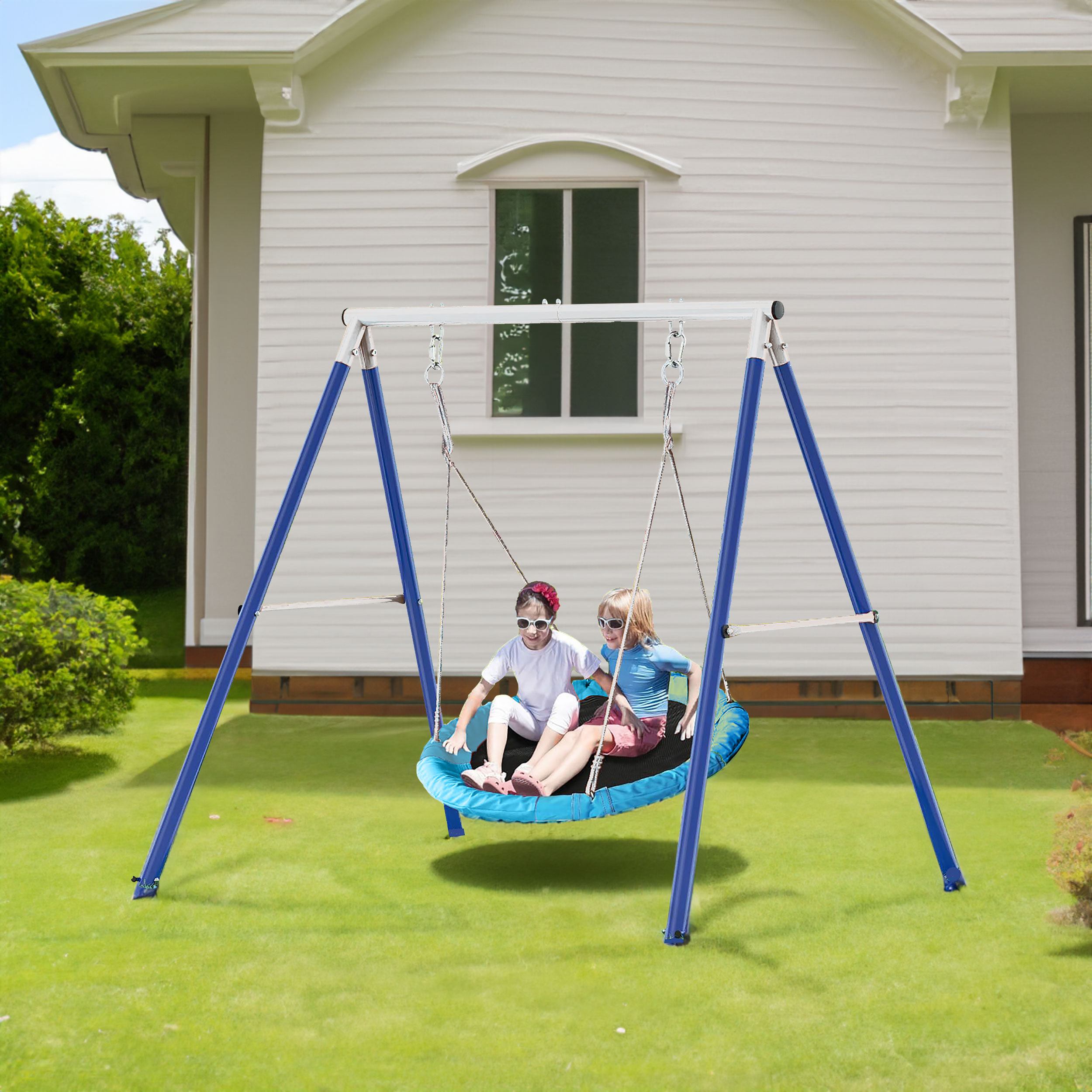 Two children swinging together on a blue saucer seat outdoors