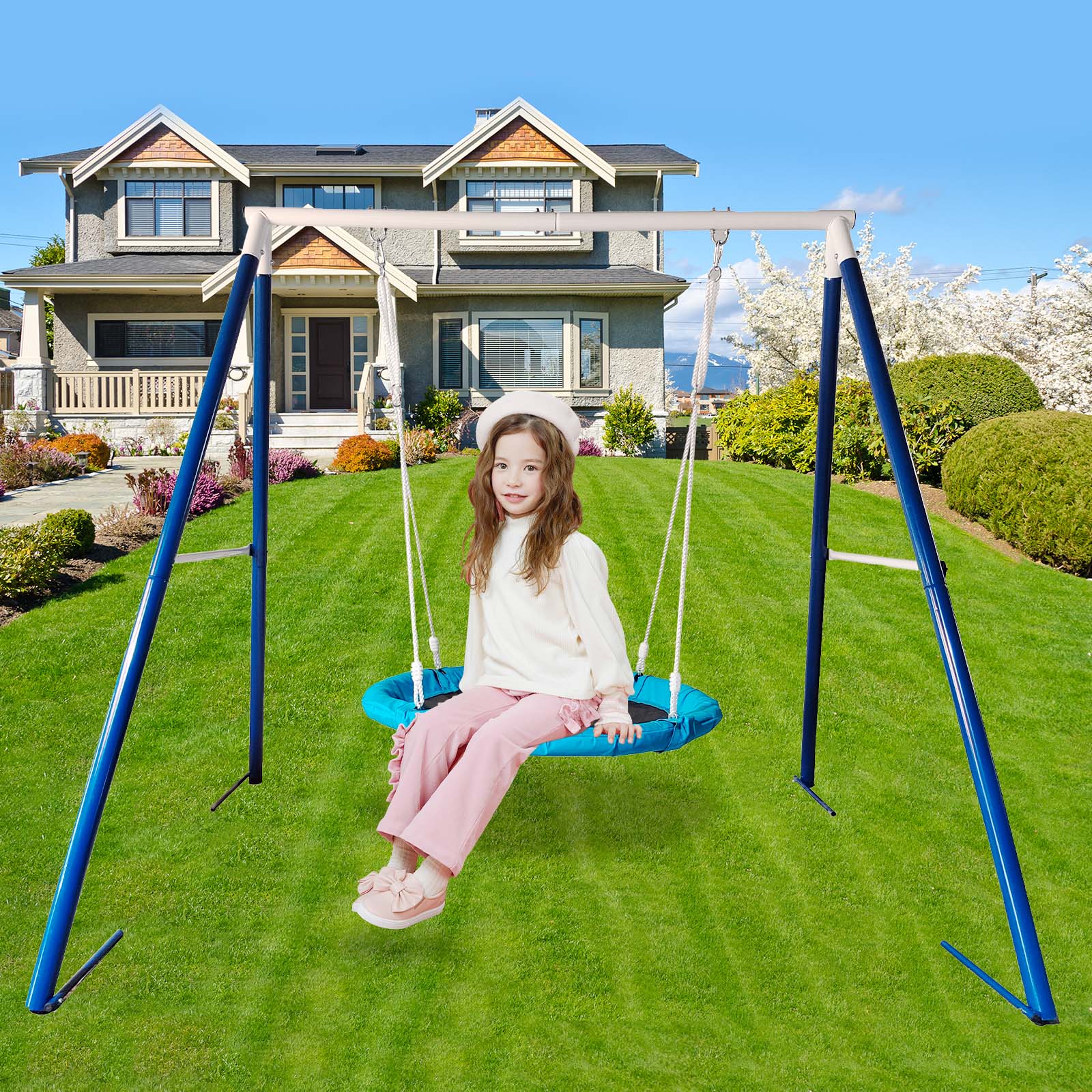 Young girl smiling on a turquoise saucer swing in front of a suburban house