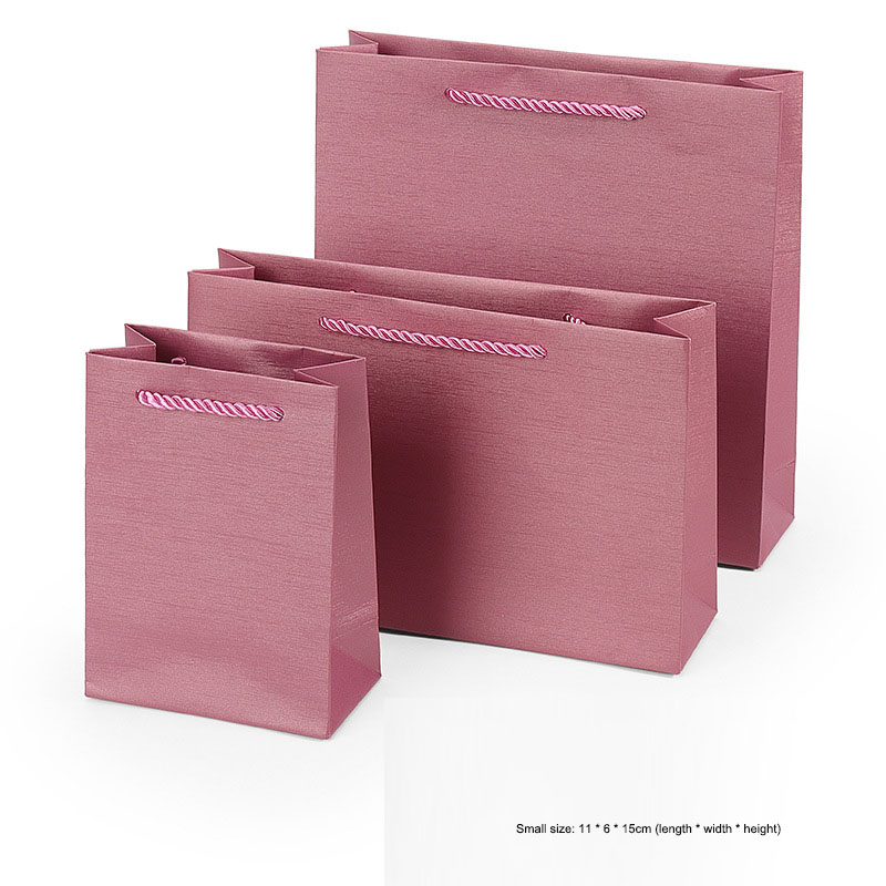 Dusty rose paper gift bag with striped cord handle in close view