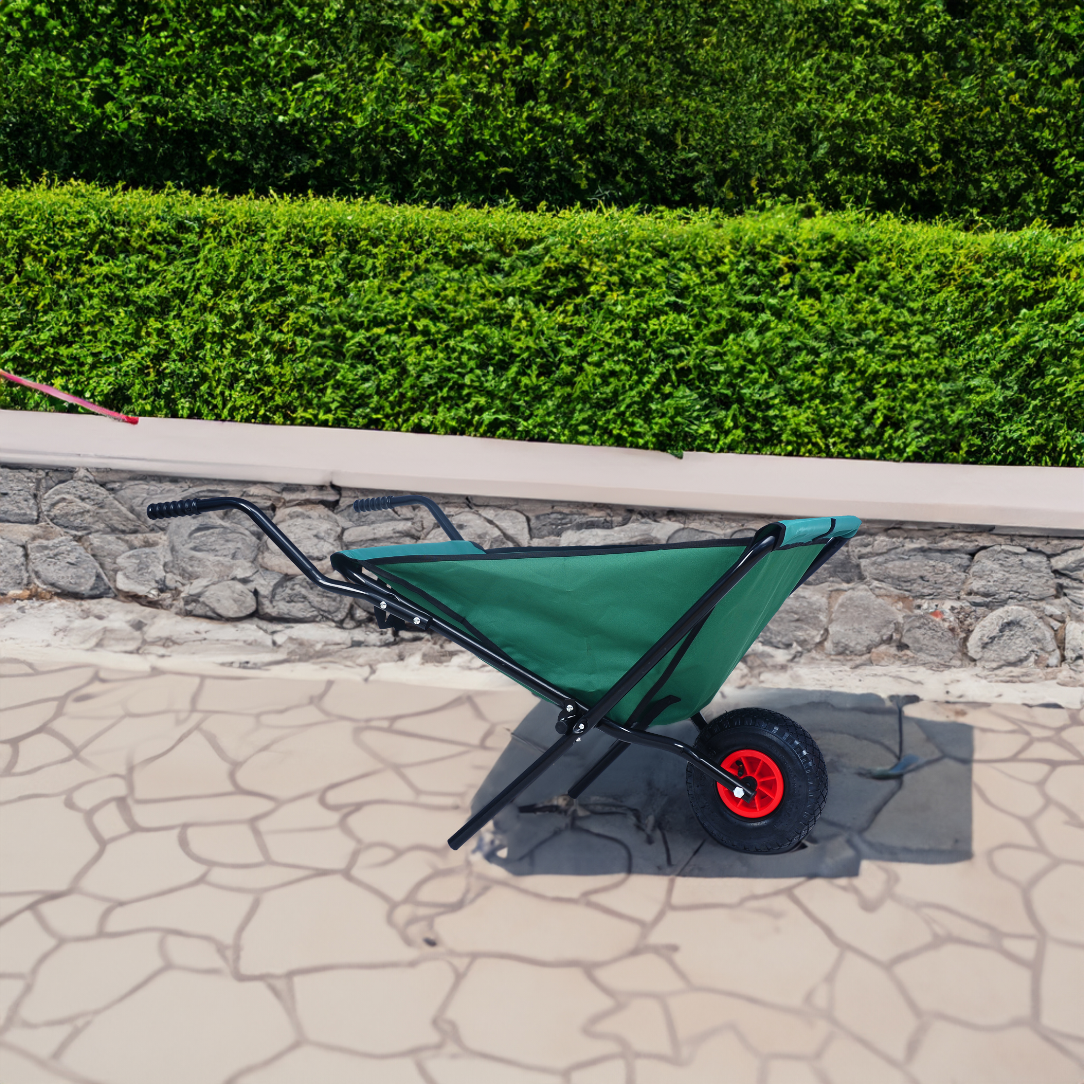Green garden cart parked on patio beside hedge
