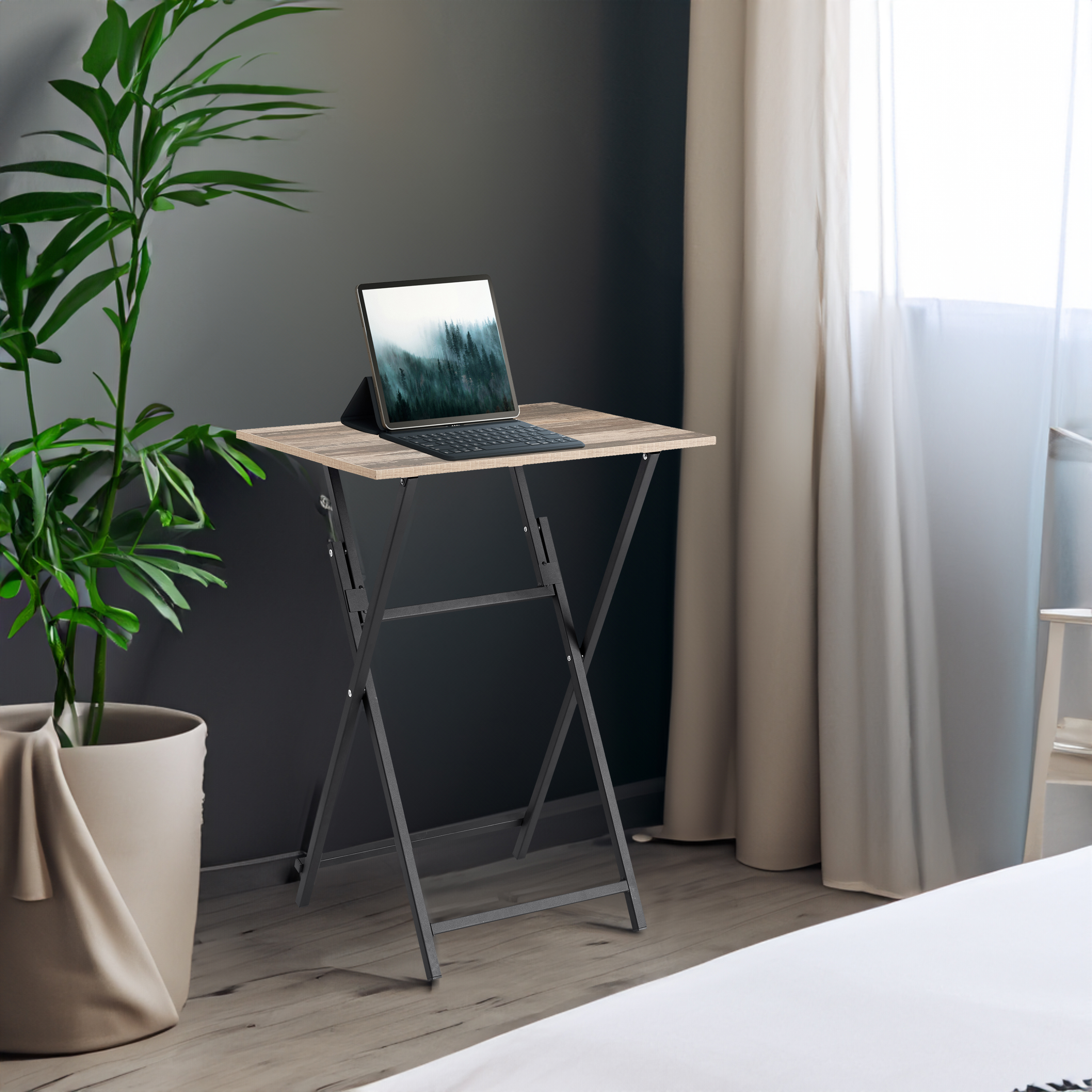 Brown woodgrain folding table beside a plant holding a tablet and keyboard