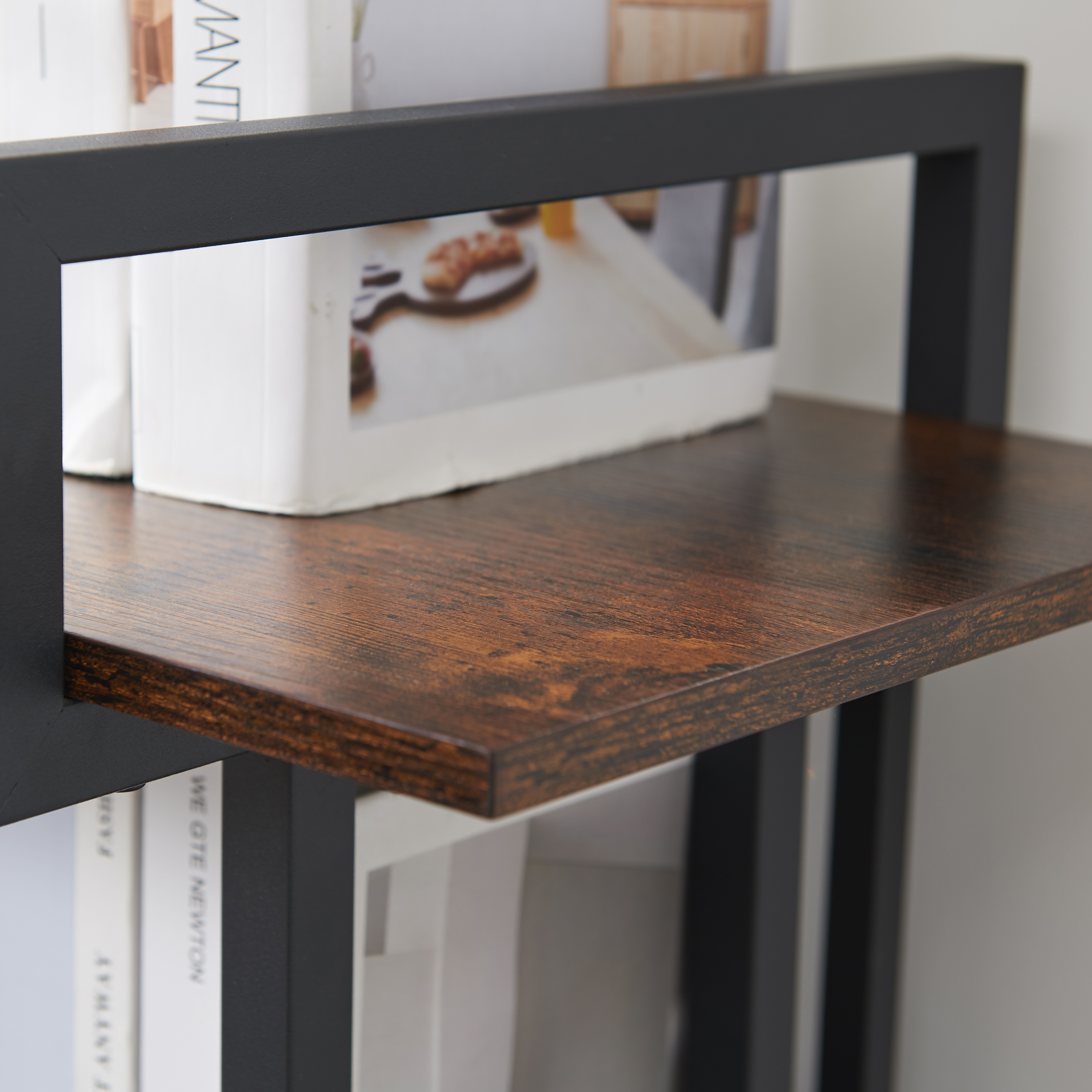 Black metal bracket and walnut-effect shelf board holding books