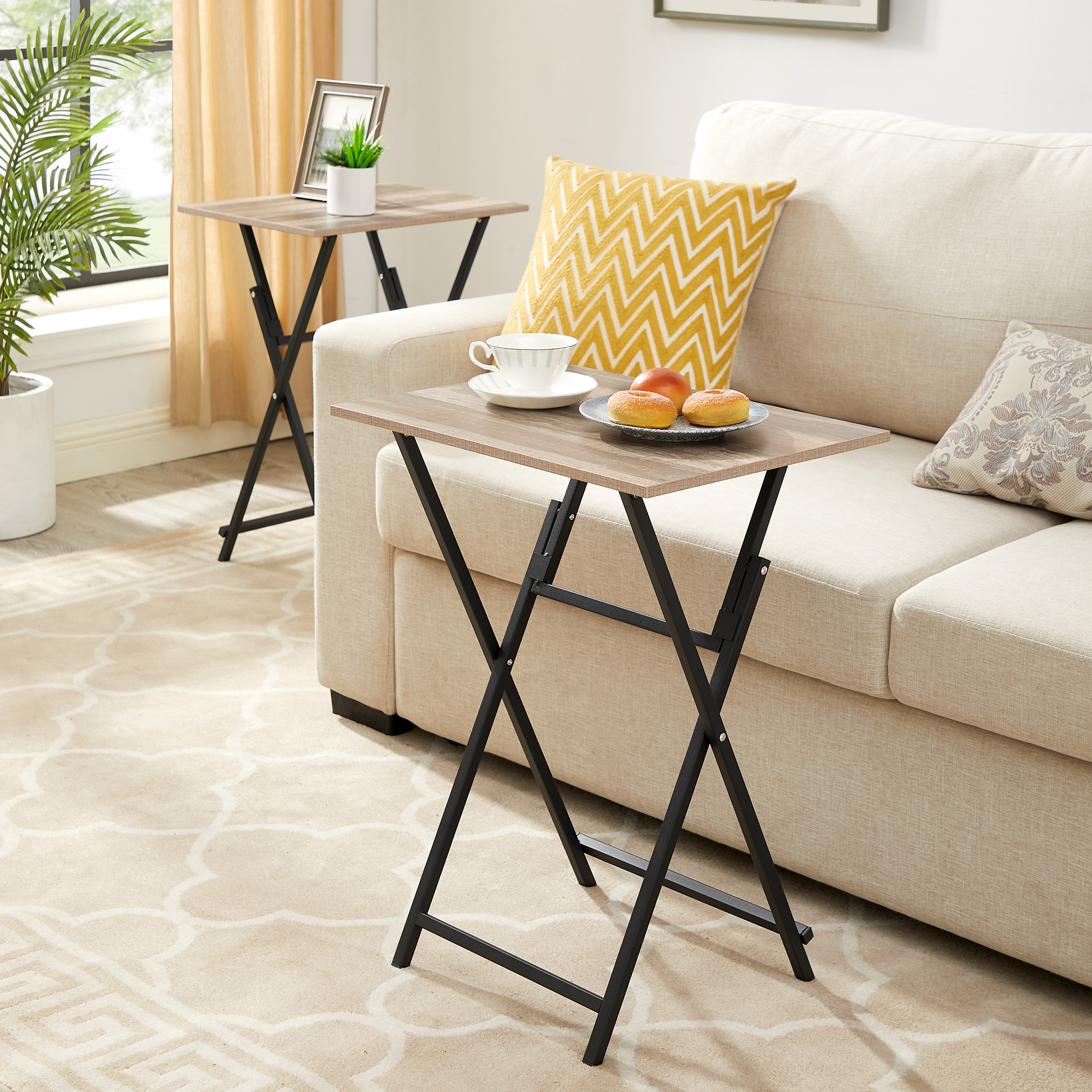 Folding tray table beside a cream sofa with tea and donuts