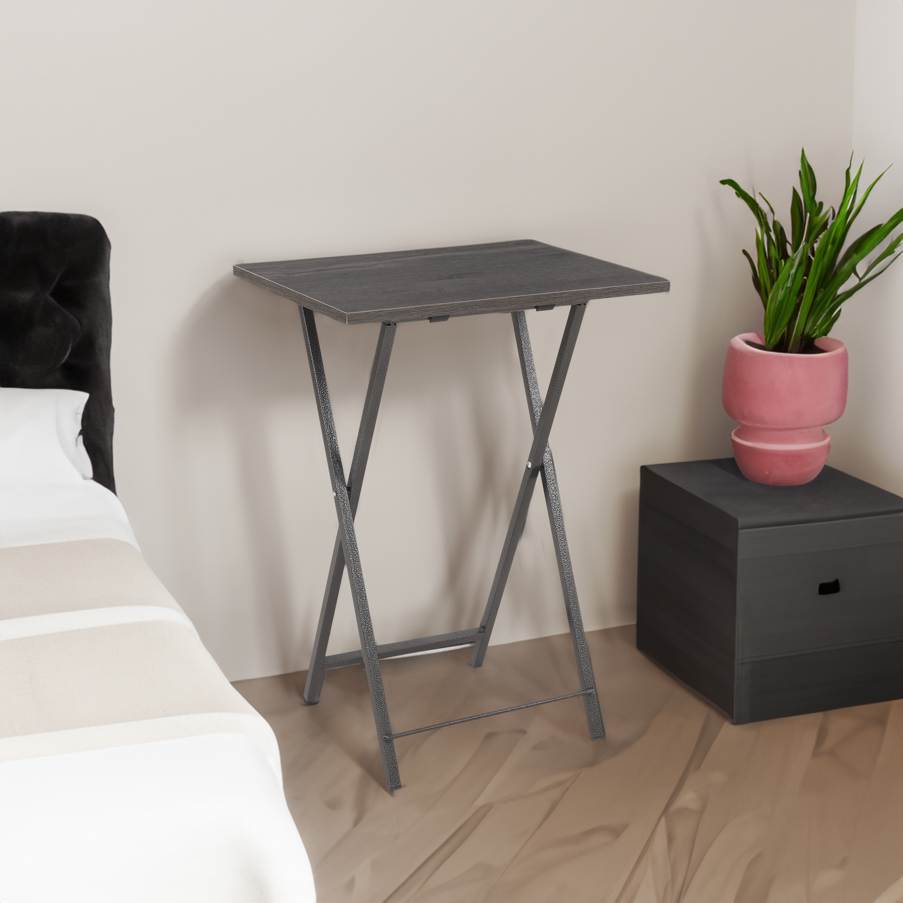 Gray folding tray placed beside a bed in a bedroom