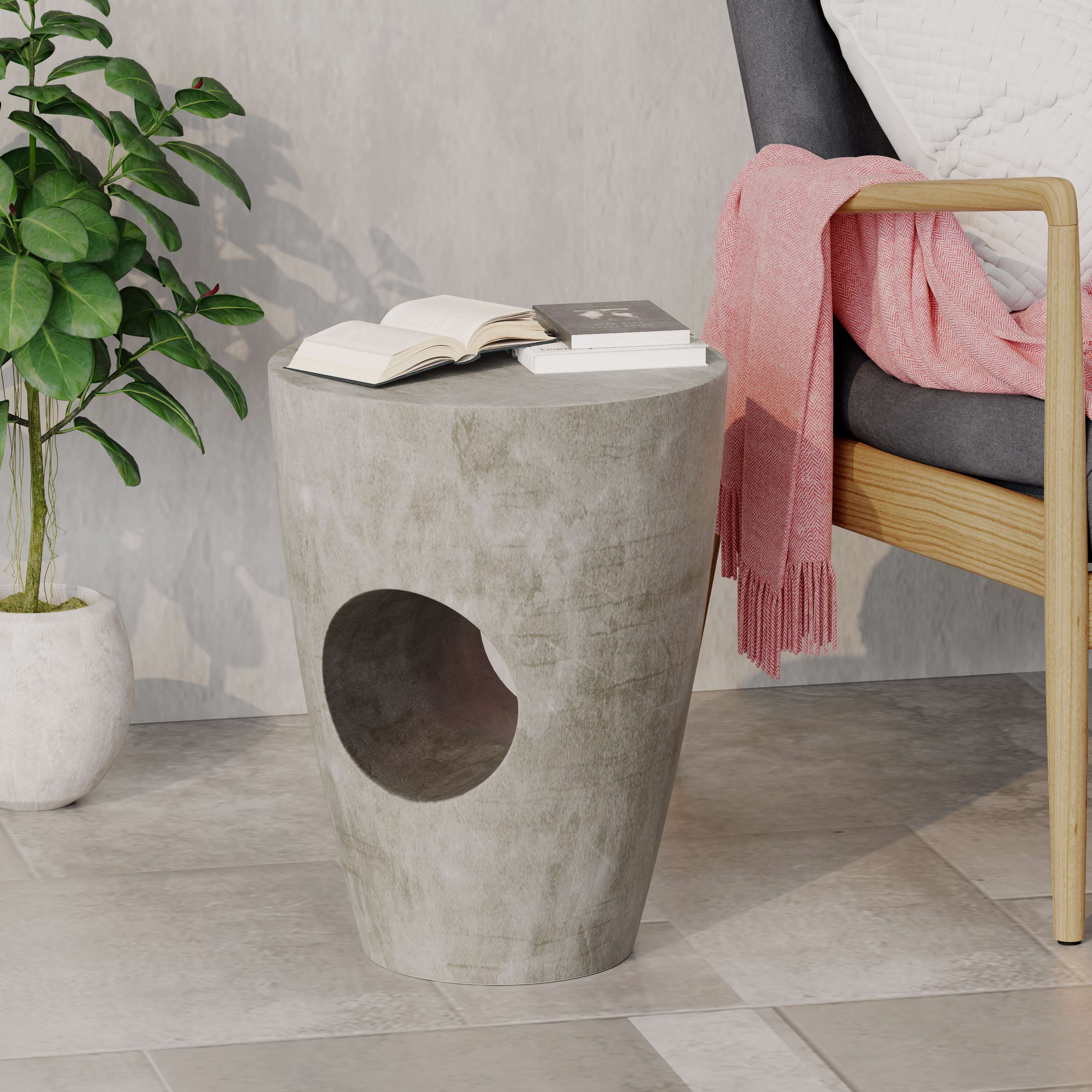Concrete-look side table holding open books beside a wooden armchair