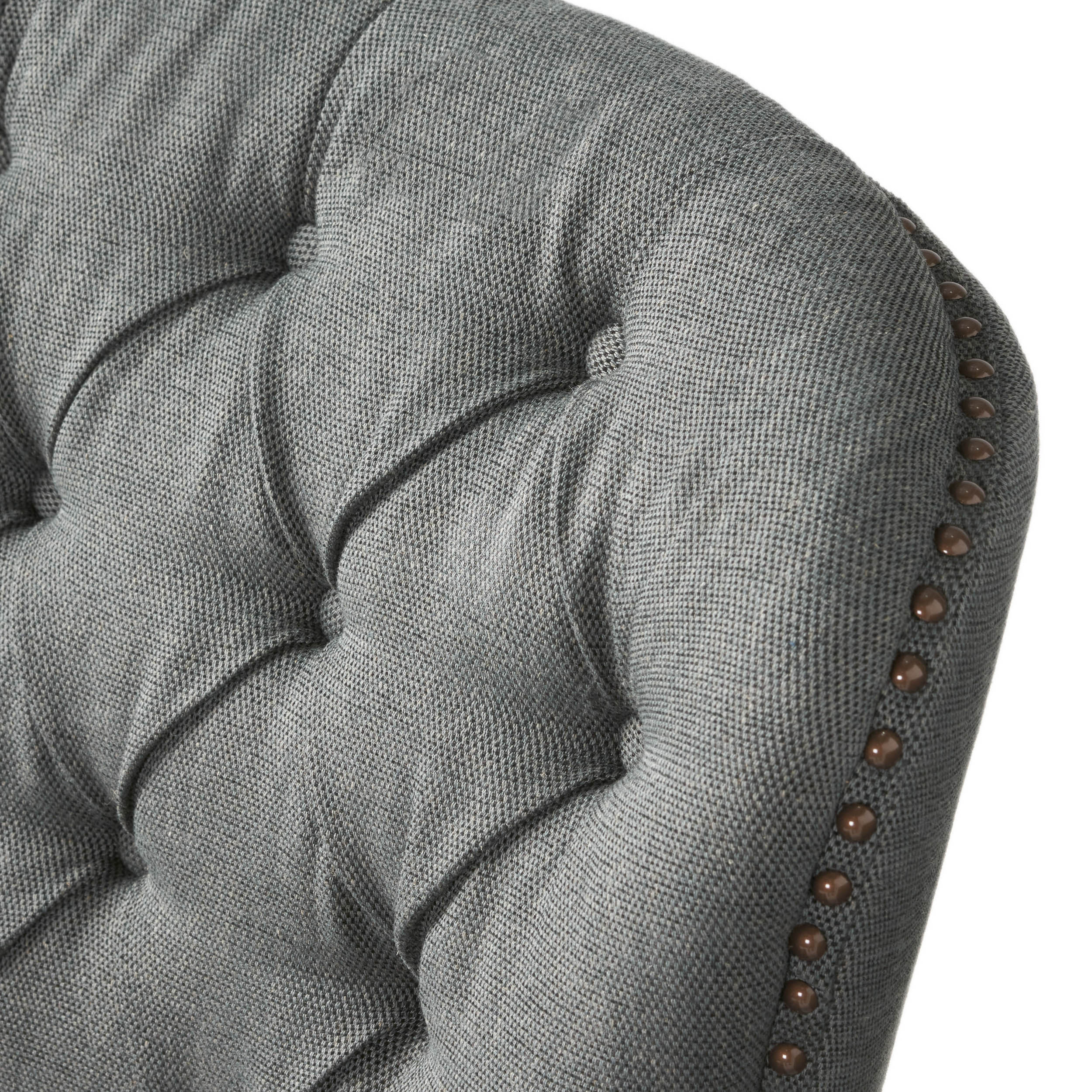 Close-up of button-tufted back and bronze nailhead trim along the arm