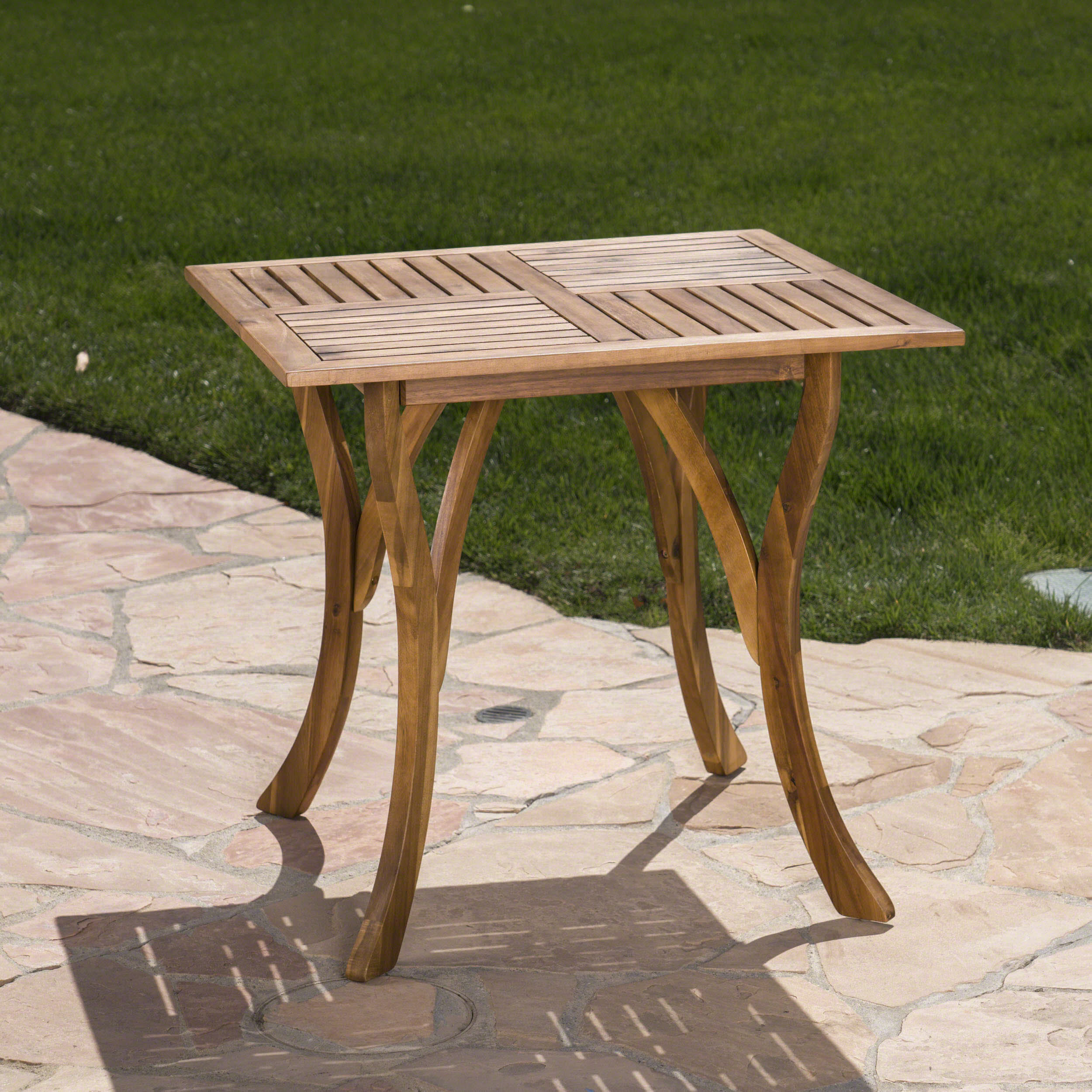Slatted teak-finish tabletop and curved legs photographed from a low angle