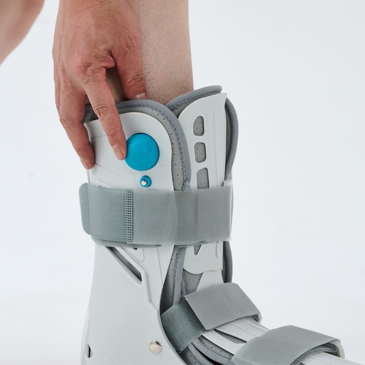 Finger pressing blue pump button on ankle boot to adjust airbag pressure