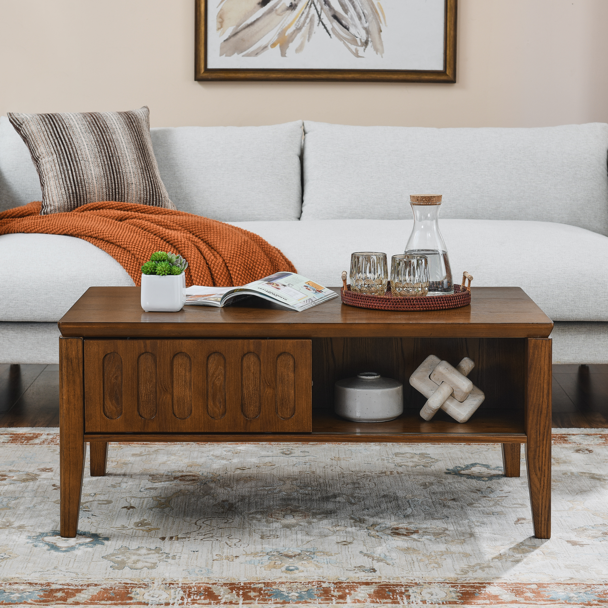 Styled walnut coffee table with glasses, carafe and magazine in a bright room