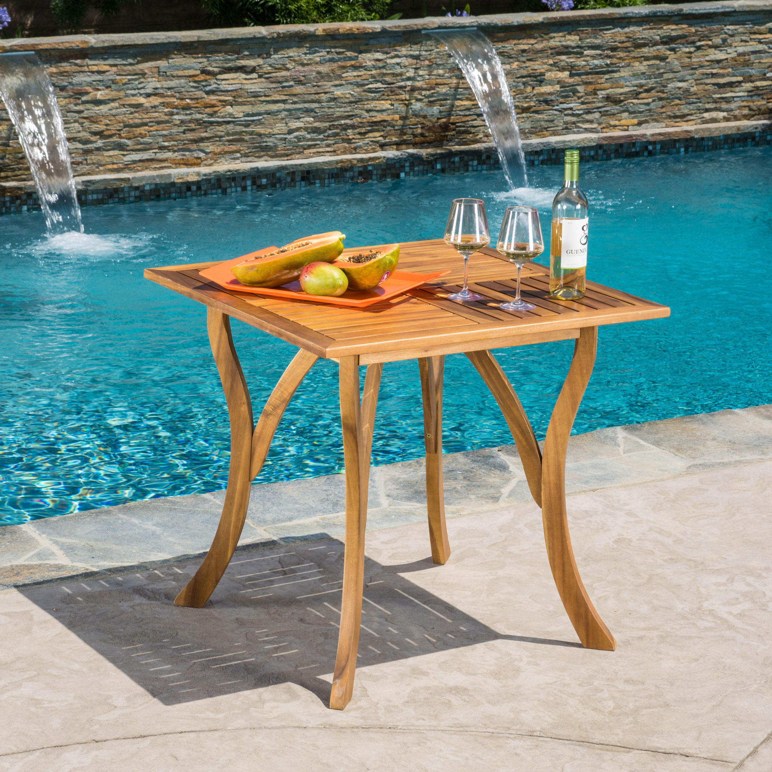 Square wood table set with fruit and two glasses for an outdoor dinner